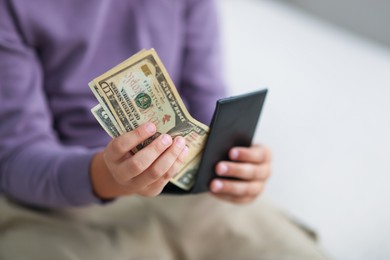 Photo of Boy putting his pocket money into wallet at home, closeup
