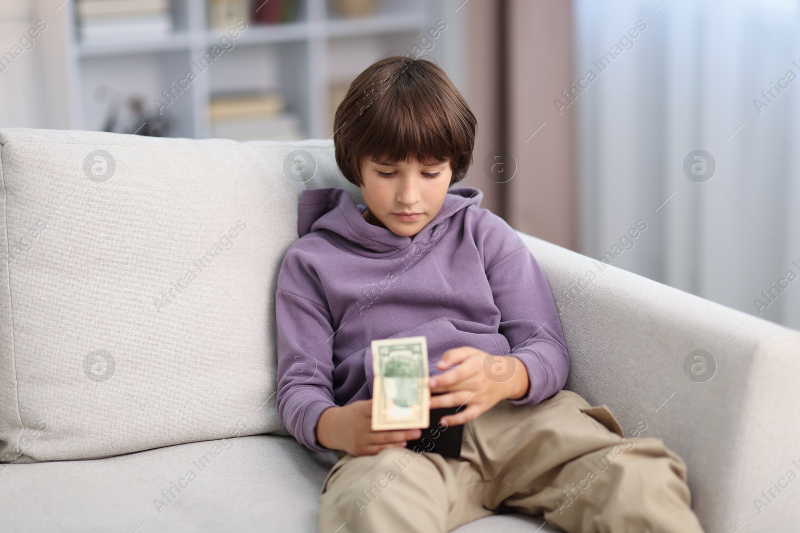 Photo of Boy with pocket money on sofa at home