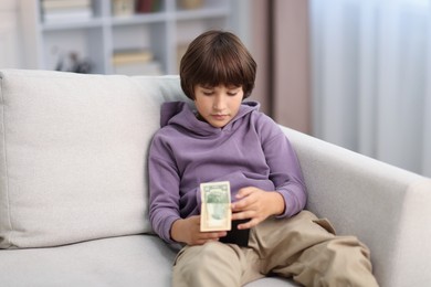Photo of Boy with pocket money on sofa at home