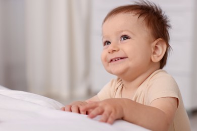Photo of Cute little baby near bed at home