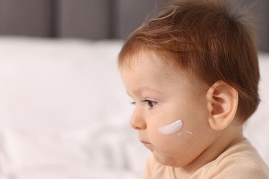 Photo of Cute baby with cream on his face at home