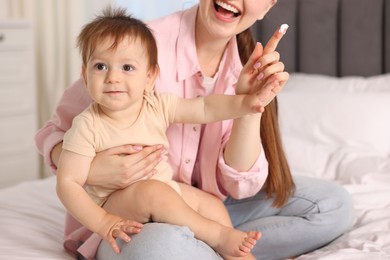 Photo of Mother applying cream onto her baby's body on bed at home