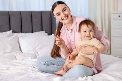 Photo of Mother applying cream onto her baby's body on bed at home