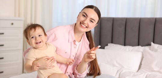 Photo of Mother applying cream onto her baby's body on bed at home