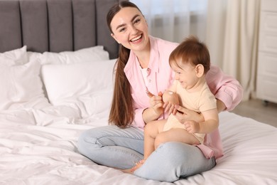 Photo of Mother applying cream onto her baby's arm on bed at home