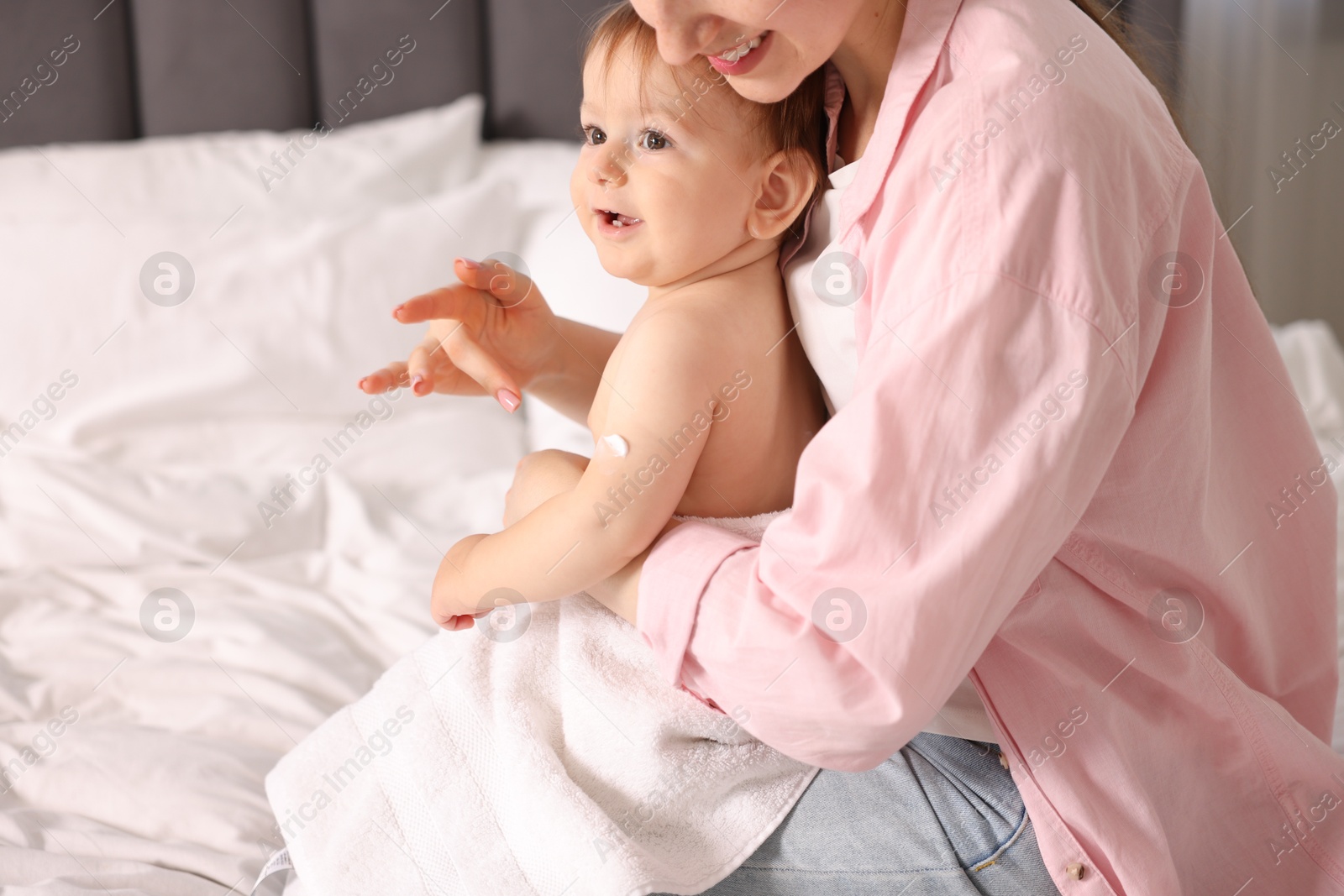 Photo of Mother applying cream onto her baby's arm at home, closeup