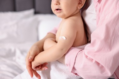 Photo of Mother and baby with cream on his arm at home, closeup