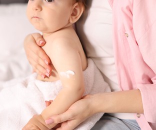 Photo of Mother and baby with cream on his arm at home, closeup