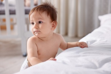 Photo of Cute little baby near bed at home