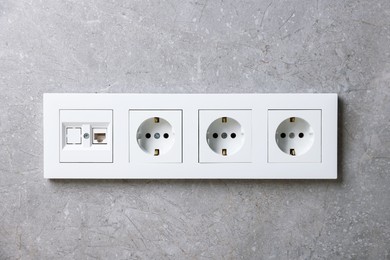 Photo of Electric power sockets on grey wall indoors
