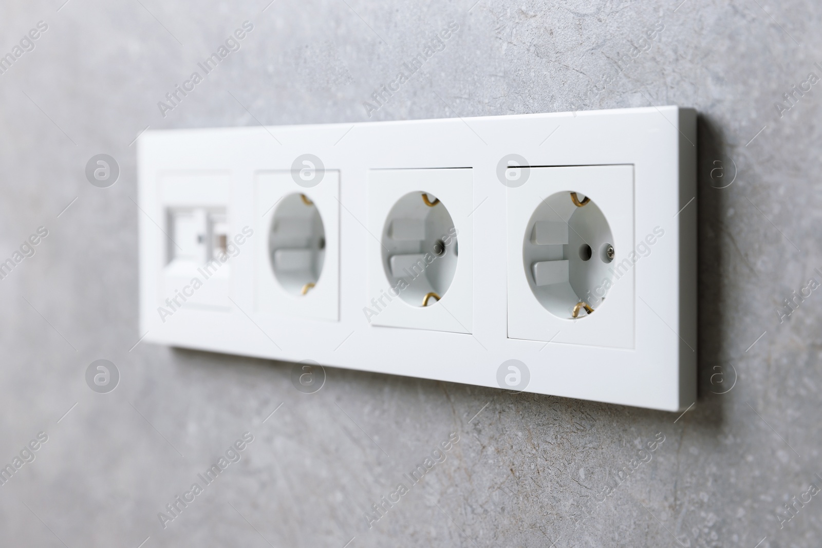 Photo of Electric power sockets on grey wall, closeup