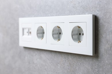 Photo of Electric power sockets on grey wall, closeup