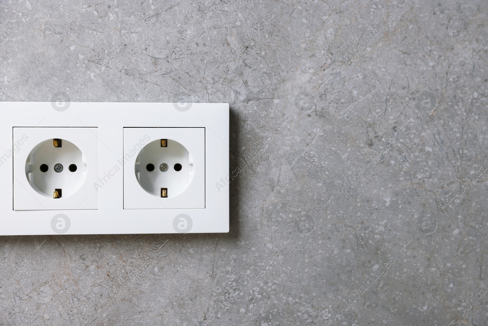 Photo of Electric power sockets on grey wall, space for text