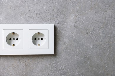 Photo of Electric power sockets on grey wall, space for text