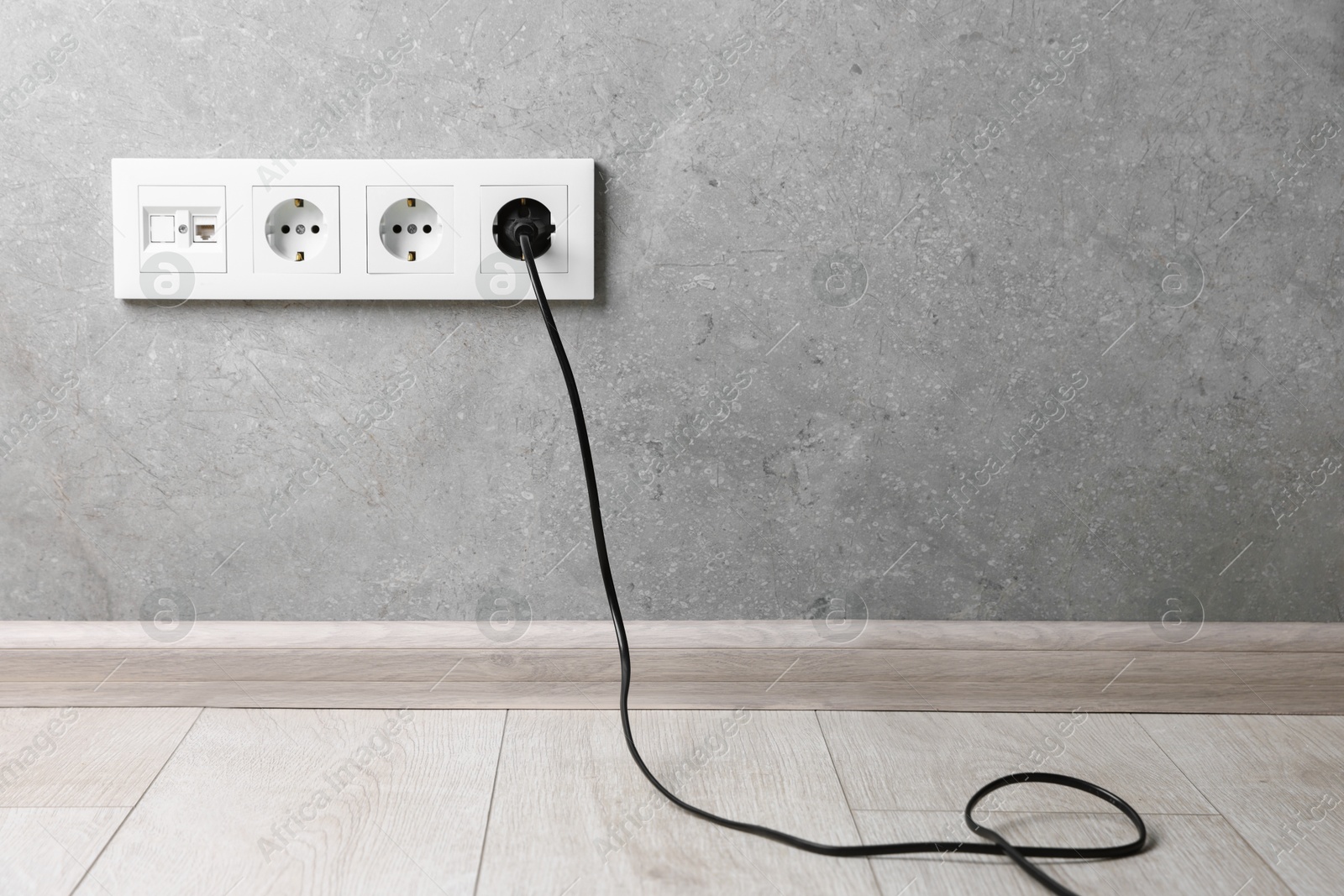 Photo of Power plug in socket on grey wall, space for text
