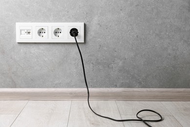 Photo of Power plug in socket on grey wall, space for text