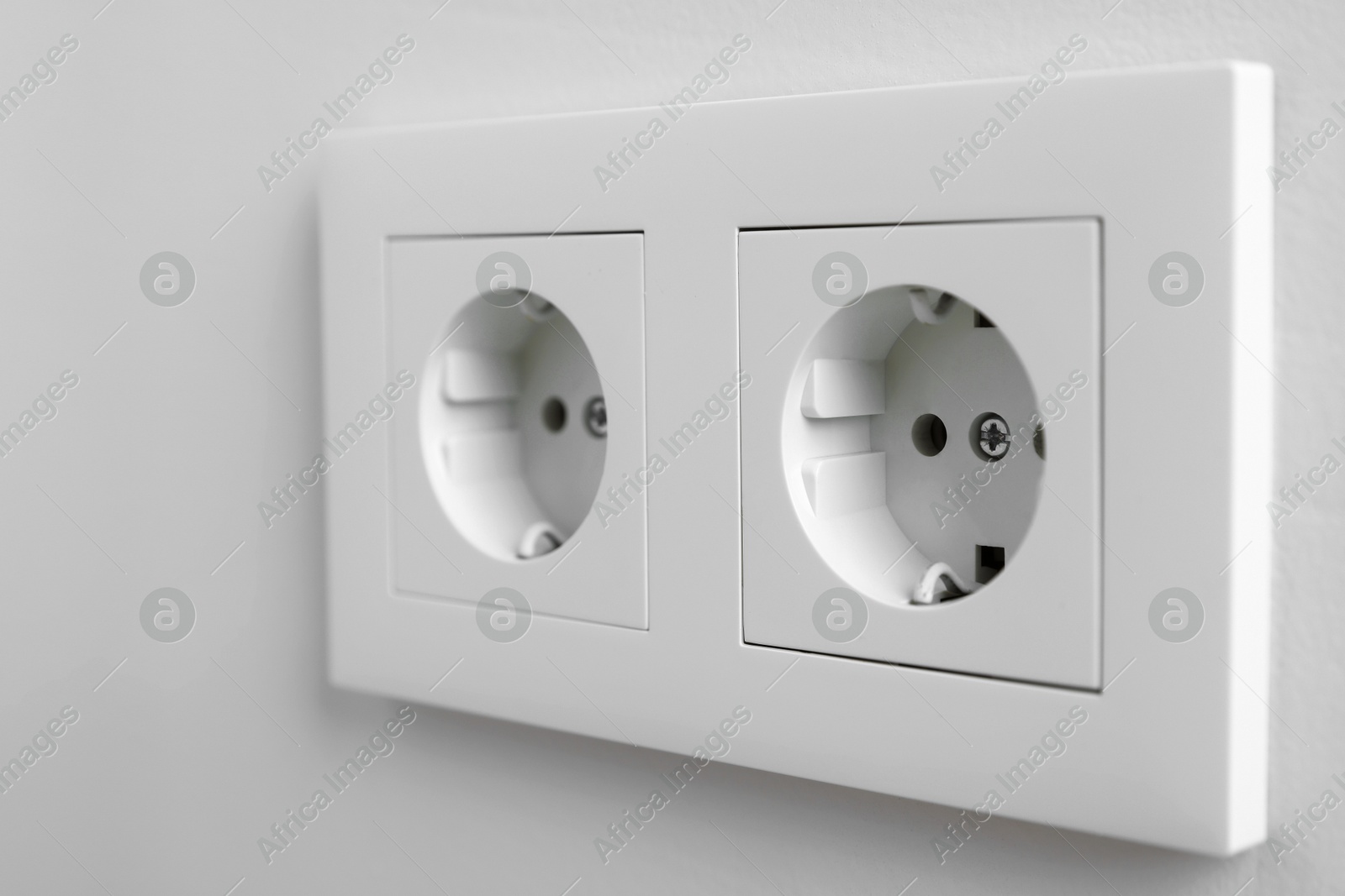 Photo of Electric power sockets on white wall, closeup