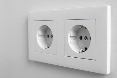 Photo of Electric power sockets on white wall, closeup