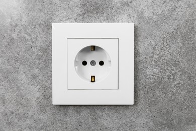 Photo of Electric power socket on grey wall indoors