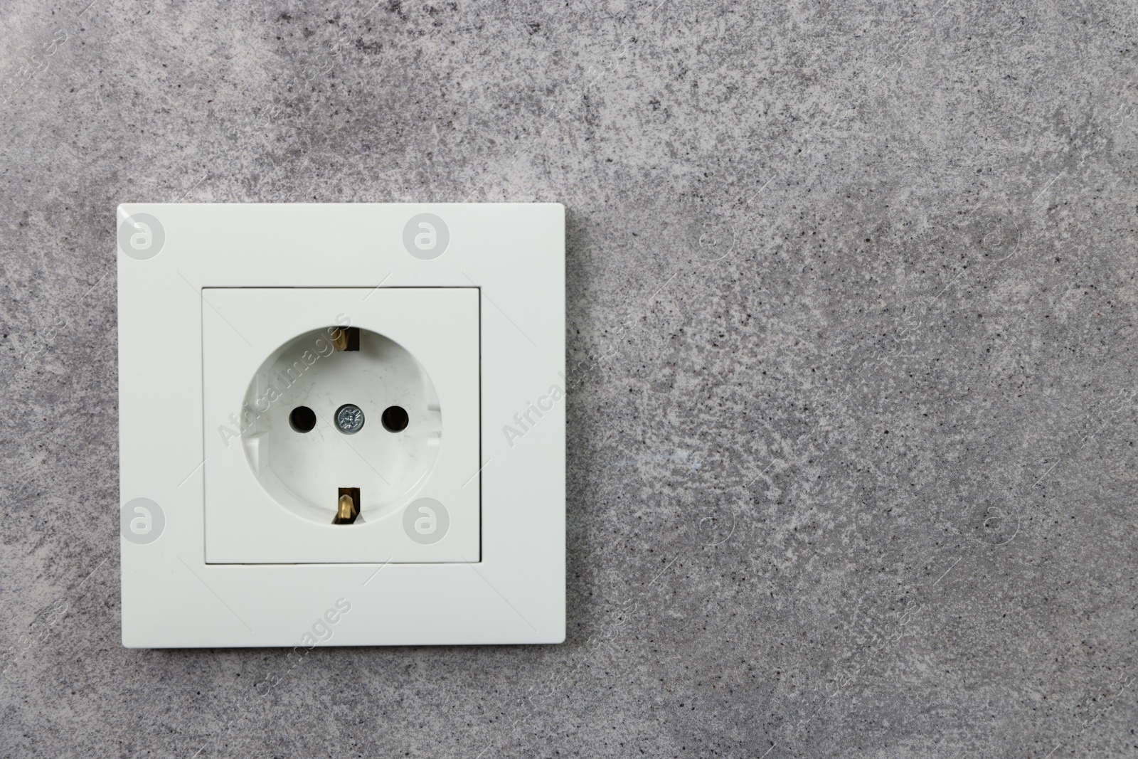 Photo of Electric power socket on grey wall, space for text