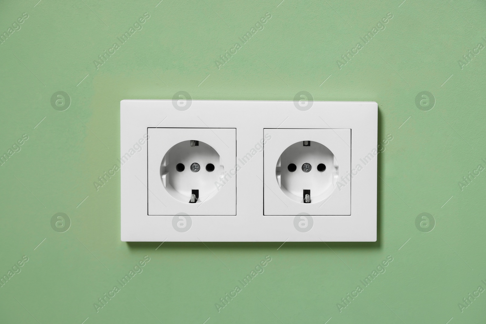 Photo of Electric power sockets on green wall indoors