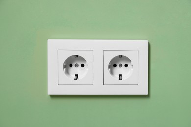 Photo of Electric power sockets on green wall indoors