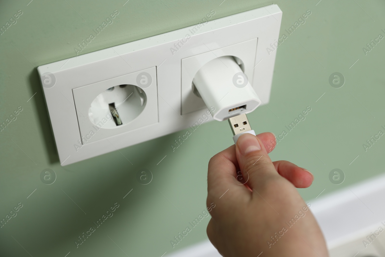 Photo of Woman inserting charge cable into USB adapter indoors, above view
