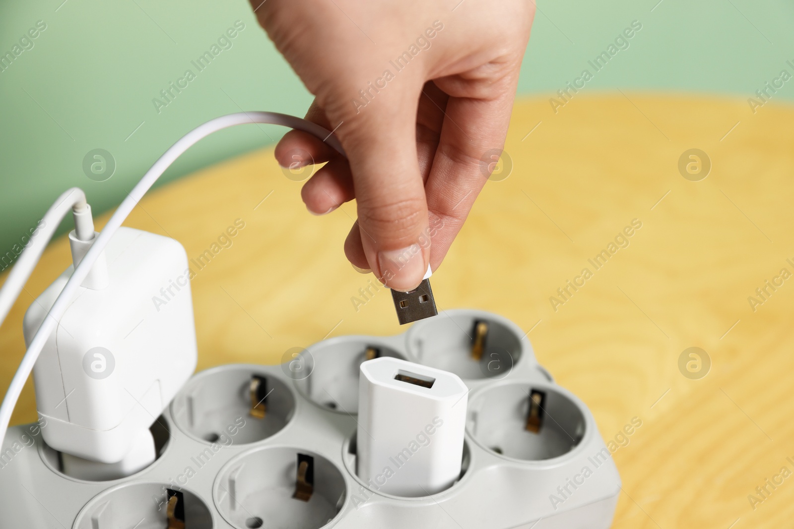 Photo of Woman inserting charge cable into USB adapter at table, closeup