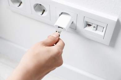 Photo of Woman inserting charge cable into USB adapter indoors, above view