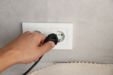 Photo of Man putting plug into power socket indoors, closeup