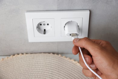 Photo of Man inserting charge cable into USB adapter indoors, closeup