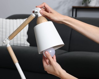 Photo of Woman changing light bulb in lamp at home, closeup