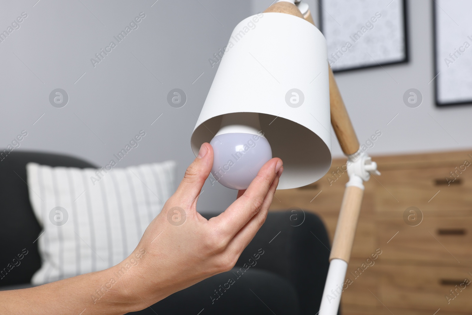 Photo of Woman changing light bulb in lamp at home, closeup