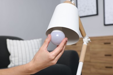 Photo of Woman changing light bulb in lamp at home, closeup
