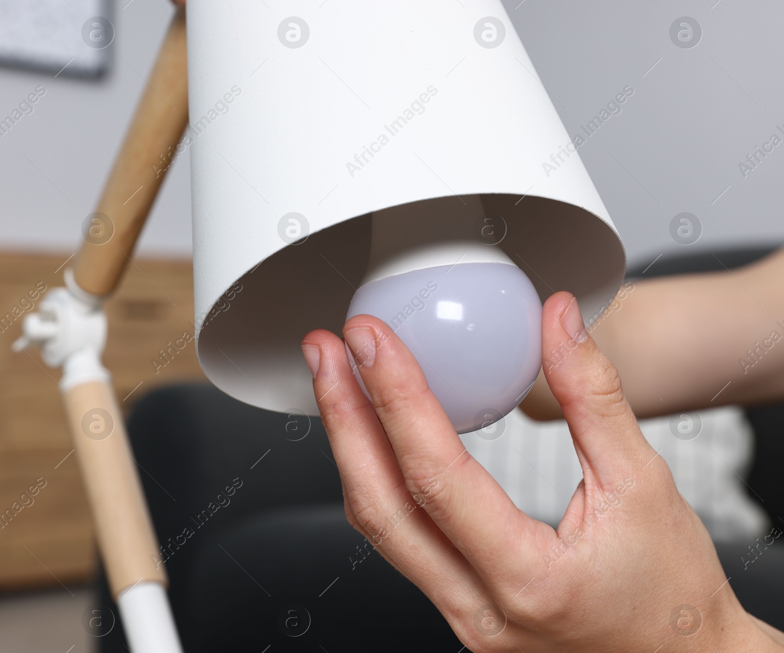Photo of Woman changing light bulb in lamp at home, closeup