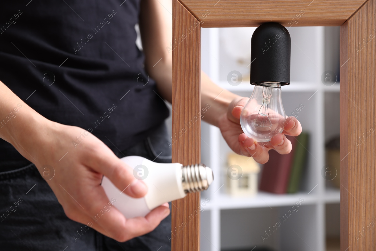 Photo of Woman changing light bulb in lamp at home, closeup