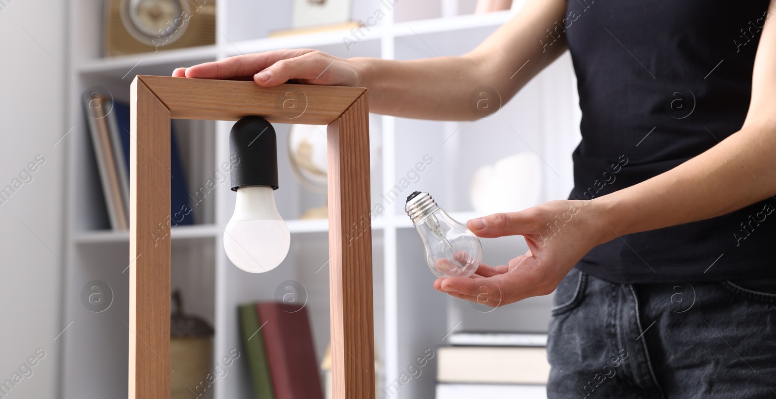 Photo of Woman changing light bulb in lamp at home, closeup