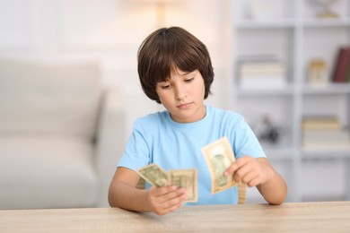 Photo of Boy with pocket money at wooden table indoors