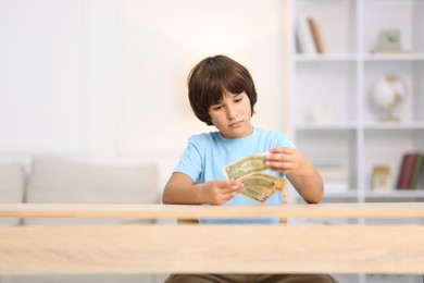 Photo of Boy with pocket money at wooden table indoors