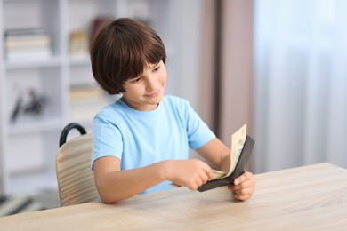 Photo of Boy with pocket money at wooden table indoors