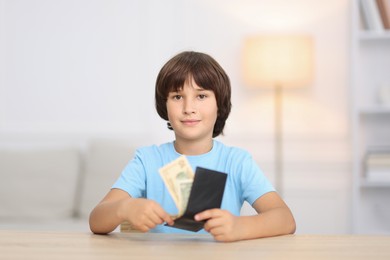 Photo of Boy with pocket money at wooden table indoors