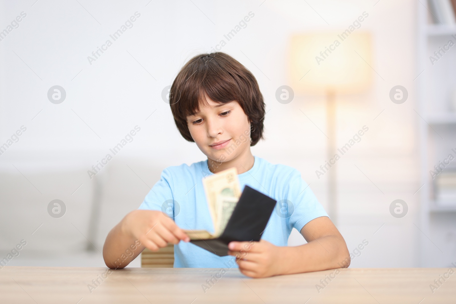 Photo of Boy with pocket money at wooden table indoors