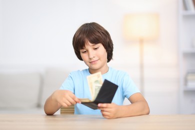 Photo of Boy with pocket money at wooden table indoors