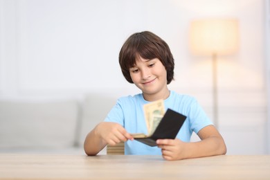 Photo of Boy with pocket money at wooden table indoors