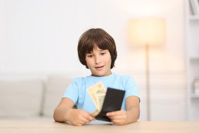 Photo of Boy with pocket money at wooden table indoors