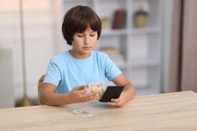 Photo of Boy with pocket money at wooden table indoors. Space for text