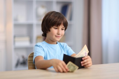 Photo of Boy with pocket money at wooden table indoors