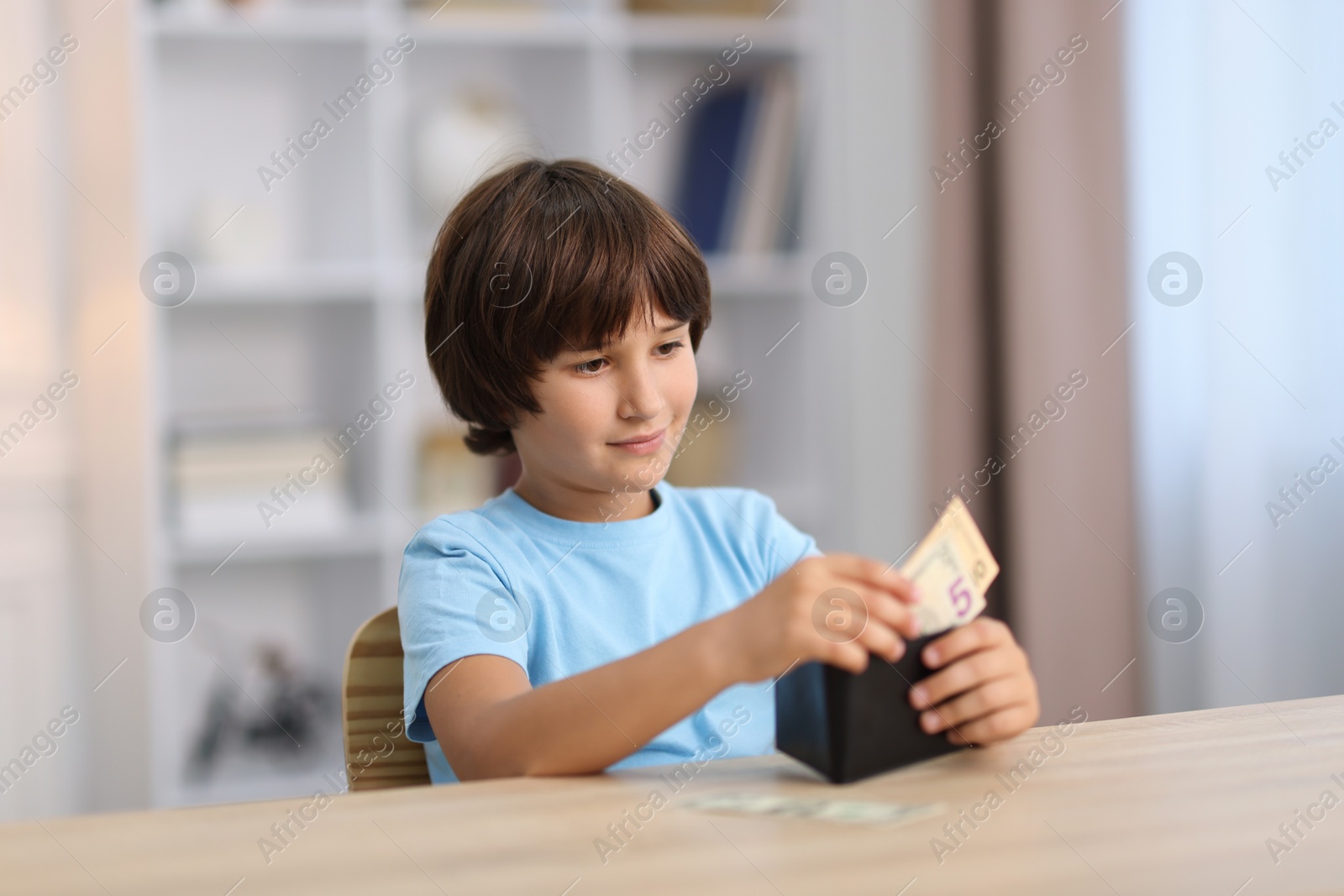 Photo of Boy with pocket money at wooden table indoors