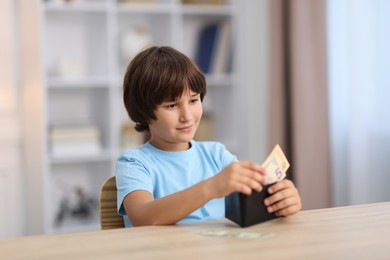 Photo of Boy with pocket money at wooden table indoors