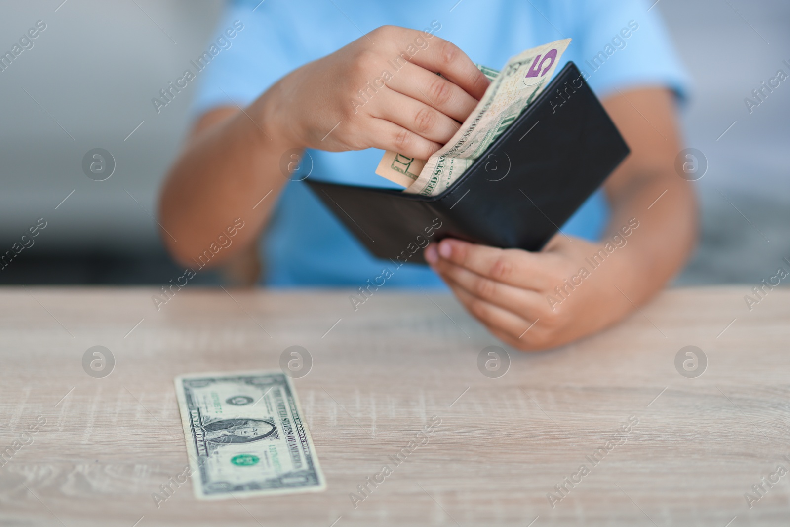 Photo of Boy with pocket money at wooden table indoors, closeup
